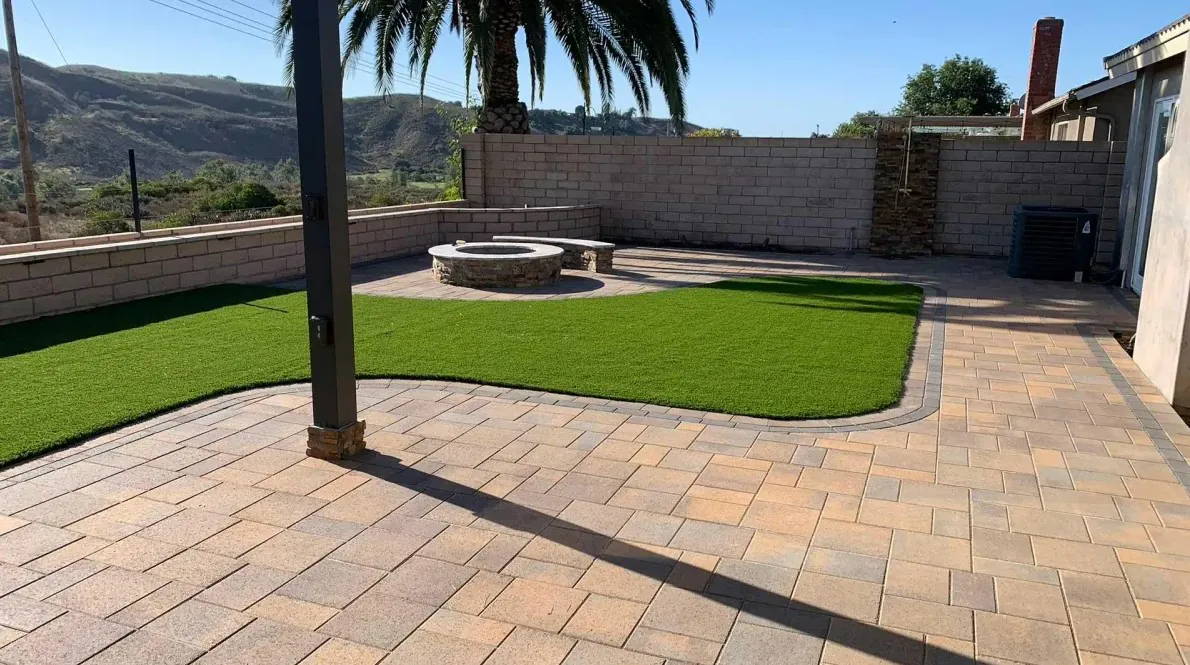 Premium backyard hardscaping with paver patio, fire feature, turf, and retaining walls