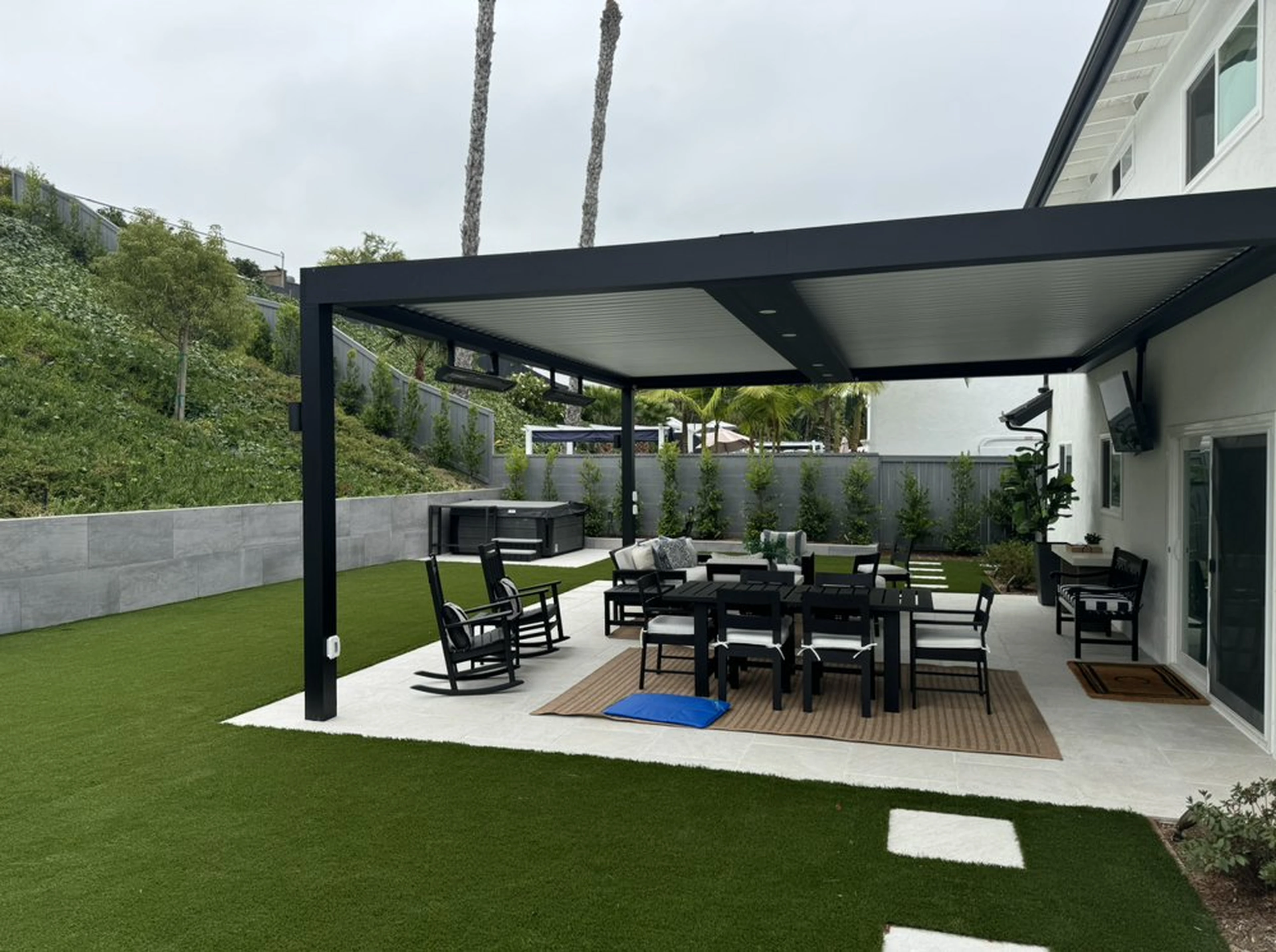 Completed Costa Mesa modern backyard with artificial turf, paver accents, and contemporary pergola