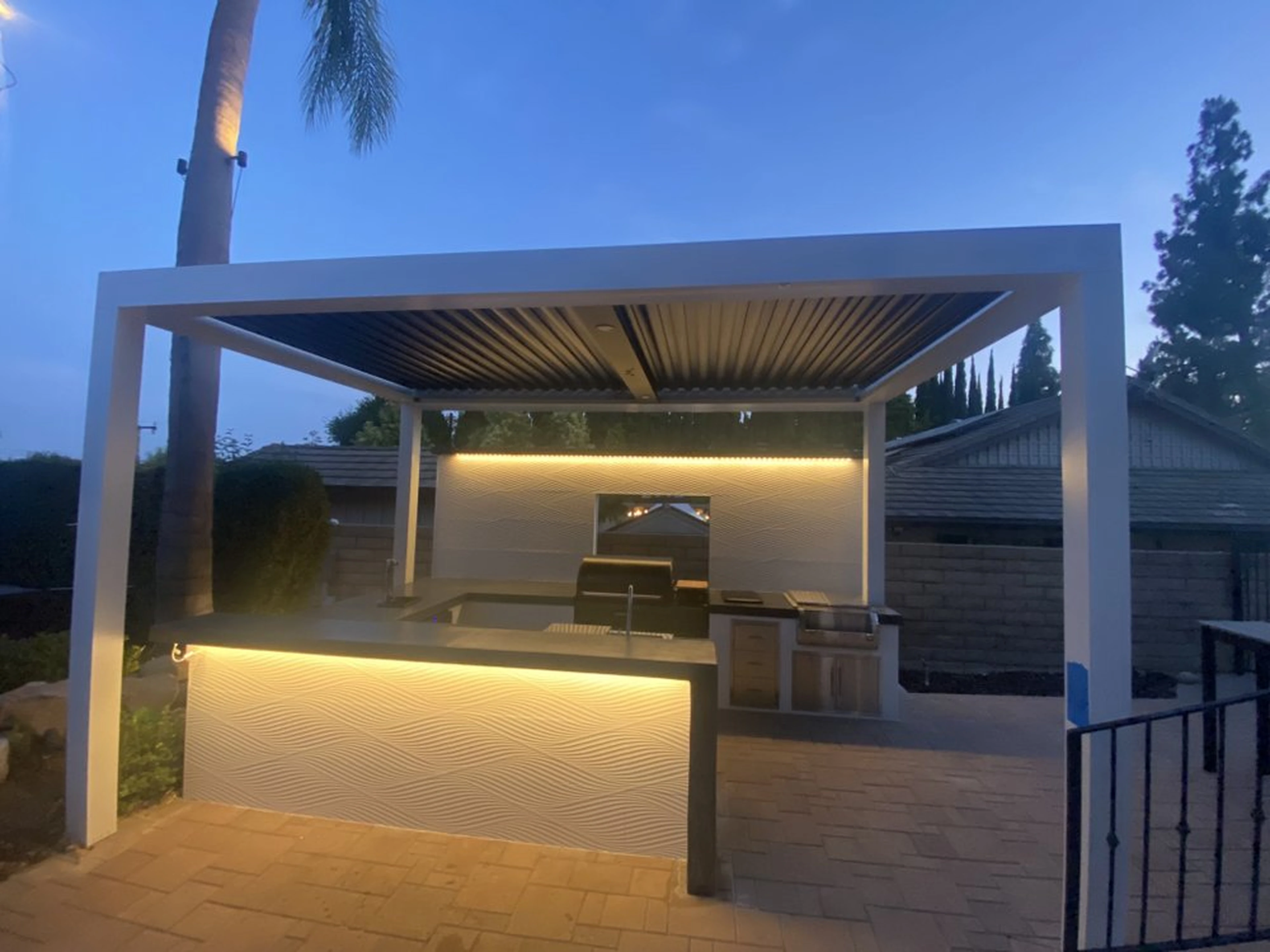 Completed Dove Canyon outdoor kitchen with illuminated pergola and built-in barbecue island