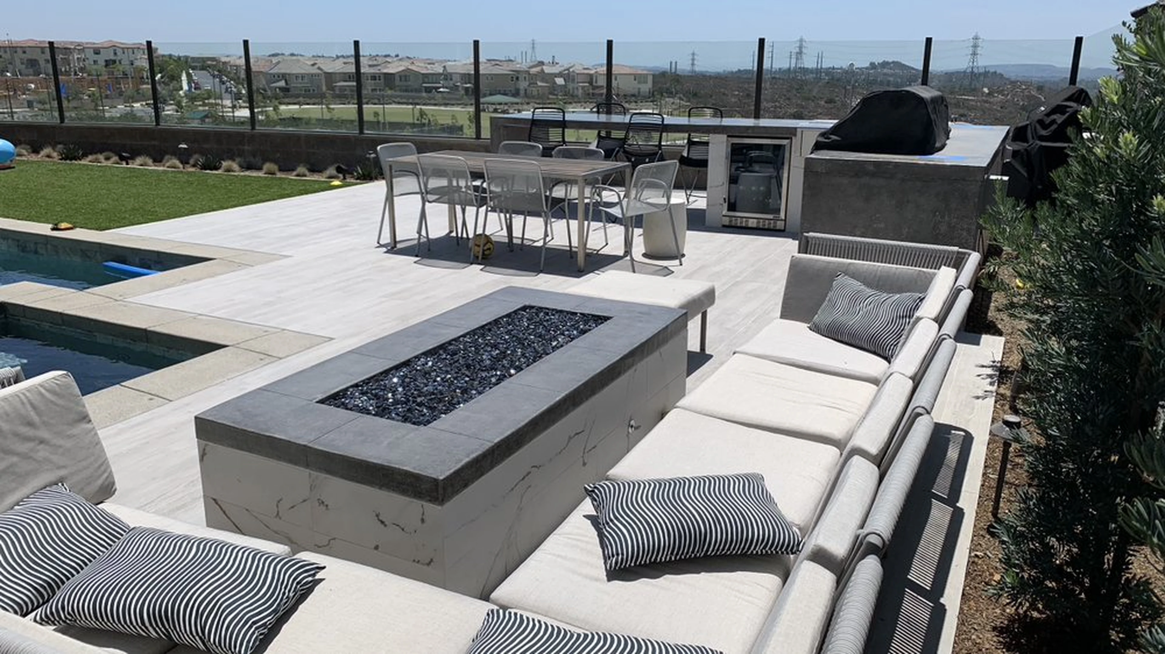 Completed Ladera Ranch outdoor entertainment area with fire table, outdoor kitchen, pool, and patio